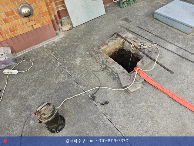 건물 앞 바닥 맨홀을 연 자리와 옆에 꺼내 둔 수중펌프